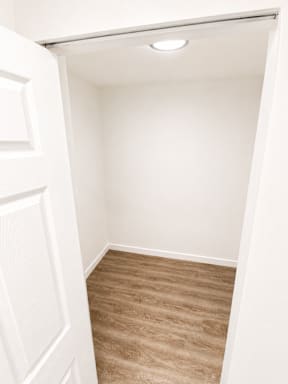 A white door is open to a room with a brown floor.