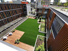 A rooftop garden with green grass and wooden planters.
