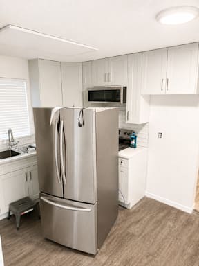 A kitchen with a stainless steel refrigerator and white cabinets.