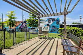 A wooden bench is situated under a wooden pergola.