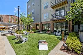 A sunny day at a modern apartment complex with a well-kept lawn and outdoor furniture.