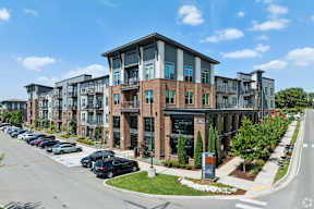 A modern apartment building with a parking lot in front.