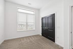 A room with a black door and a window with blinds.