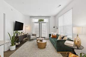 A living room with a green couch, a wooden coffee table, and a flat screen TV.