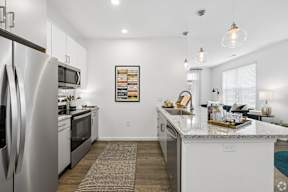 A modern kitchen with a granite countertop and stainless steel appliances.