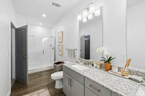 A bathroom with a toilet, sink, and mirror.