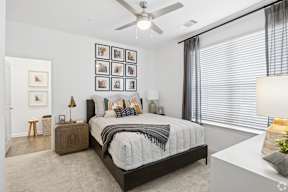 A bedroom with a bed, nightstand, and a ceiling fan.