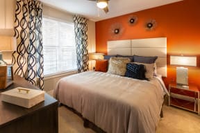 a bedroom with an orange accent wall and a large bed