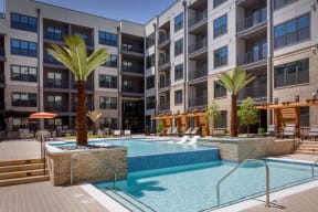 a swimming pool with palm trees in front of an apartment building