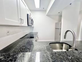 an empty kitchen with granite counter tops and a sink