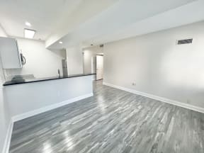 the living room and kitchen of a new home with white walls and wood flooring