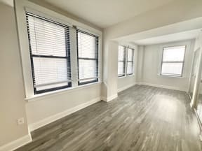 an empty living room with windows and wood floors