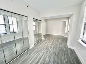 an empty living room with mirrored doors and a large window