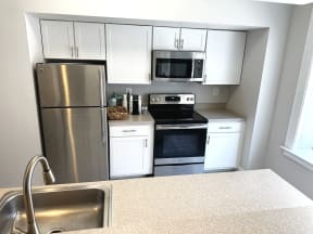 Renovated kitchen with white cabinets and stainless steel appliances