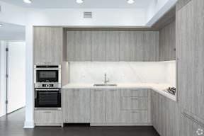 Dark finish cabinetry in a kitchen with wooden cabinets and a sink and an oven