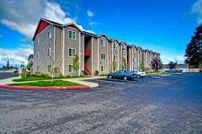 Apartment complex with a blue car parked in front.