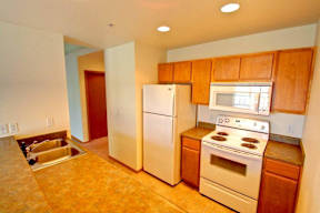 A kitchen with a stove, refrigerator, and microwave.