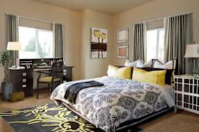 A bedroom with a large bed and a desk with a chair.