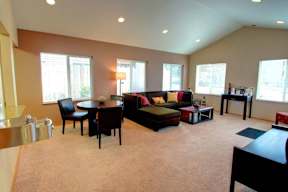 A living room with a black couch, a coffee table, and a dining table.
