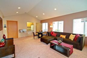 A living room with a brown couch and a red coffee table.