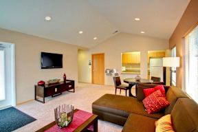 A living room with a brown couch and a television on the wall.