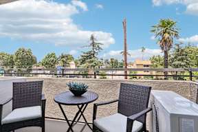 A patio with a table and chairs overlooking a street.