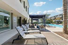 A poolside area with lounge chairs and a canopy.