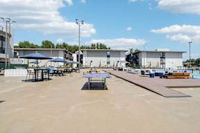 A large open area with tables and chairs and a building in the background.