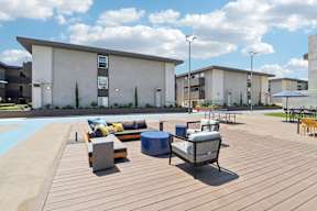 A wooden deck with a bench and a table in front of a building.