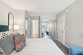A bedroom with a large bed and a blue stool.