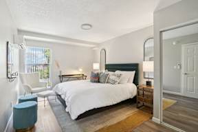 A bedroom with a large bed and a chair.
