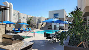 A pool area with blue umbrellas and chairs.
