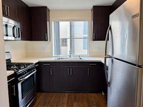 A kitchen with dark brown cabinets and a stainless steel refrigerator.
