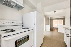 A white kitchen with a stove, oven, and refrigerator.