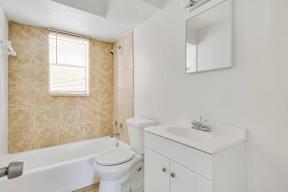 A white bathroom with a tub, sink, and mirror.