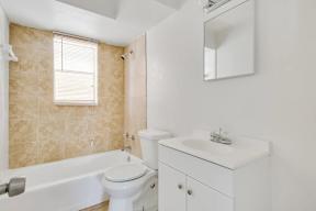 A white bathroom with a tub, sink, and mirror.