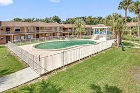 A pool surrounded by a fence in a grassy area.
