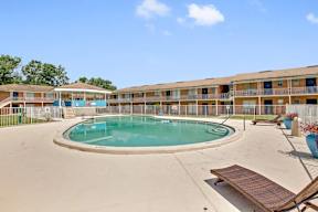 A swimming pool in front of a building with a fence around it.