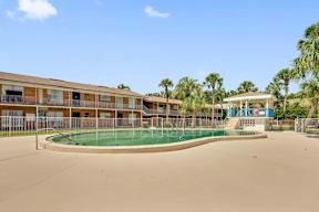 A swimming pool is surrounded by a fence and a building.