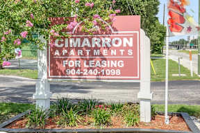 A sign for Cimarron Apartments for leasing with a phone number on it.