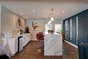 A modern kitchen with a marble island and a dining area with a table and chairs.