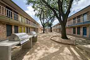 A courtyard with benches and trees surrounded by buildings.