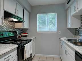 A kitchen with a black stove top oven and white cabinets.