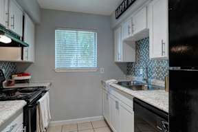 A kitchen with black appliances and white cabinets.