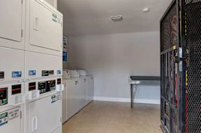 A row of washing machines are in a laundry room.