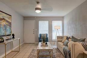 A living room with a couch, a coffee table, and a painting on the wall.