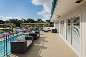 A pool area with a black couch and a white couch.