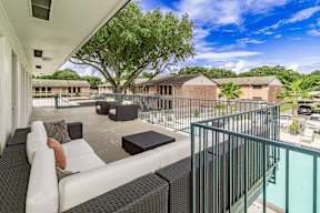 A balcony with a white couch and a black coffee table.