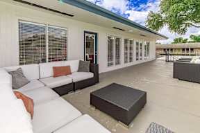 A white couch with pillows is on a patio.