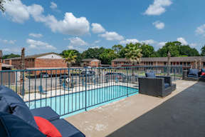 A pool area with a blue pool and a black fence.
